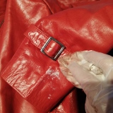 Hand rubbing feed onto red leather with buckle
