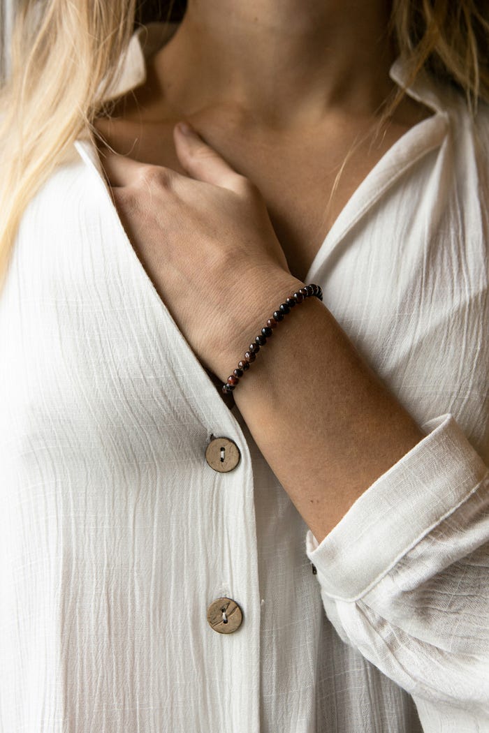Close up of neckline of textured white blouse with hand inside neckline resting on shoulder.