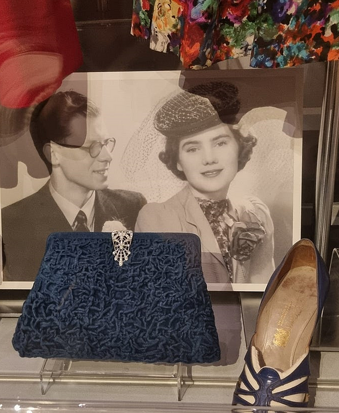 Photograph of bride and groom, the bride’s blue brocade clutch bag with diamante clasp and her blue and white shoe.